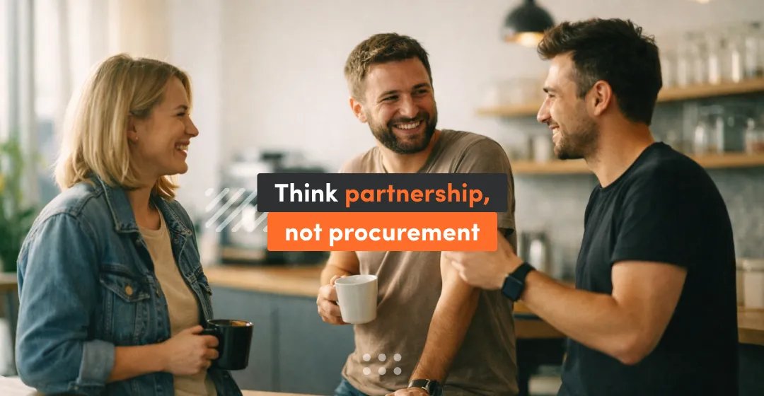 Photo of three coworkers chatting and smiling in a kitchen setting, with an overlay message that says “Think partnership, not procurement.”