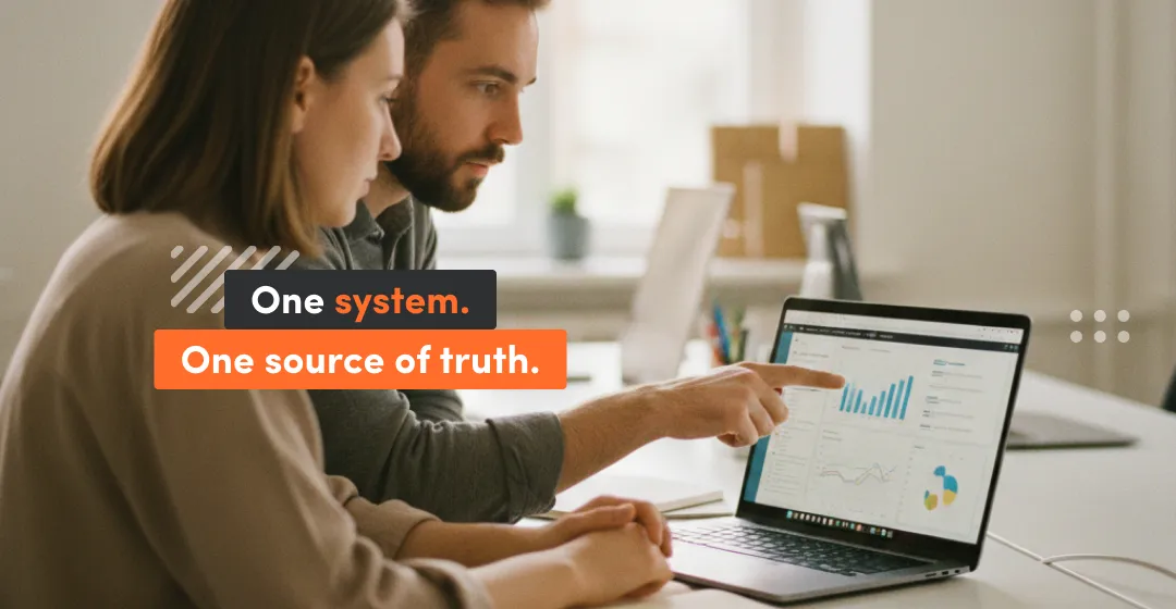 Team reviewing reporting dashboards on a laptop—one source of truth in a learning management system for employees.